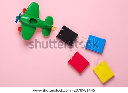Toy air plane and Miniature shopping bags on a pink background. Travel and shopping concept