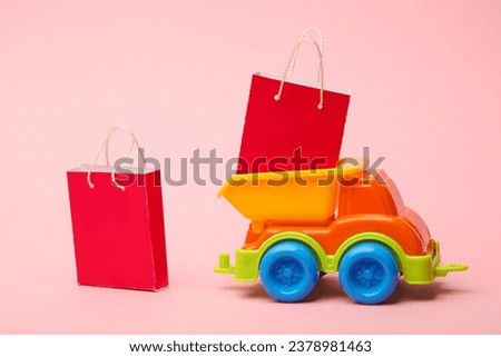 Toy dump truck with shopping bags on a pink background