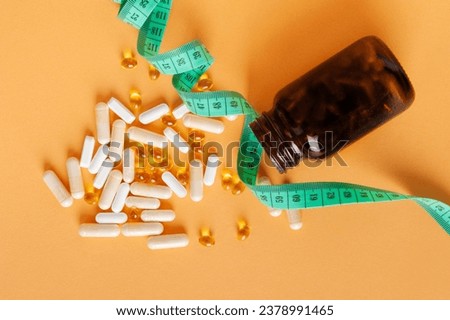 Weight Loss Pills Scattered from Bottle, Diet Supplements Capsules, Obesity Lose Tablets, Color Drugs Pile, Weight Loss Pills on Yellow Background with Copy Space for Text Royalty-Free Stock Photo #2378991465