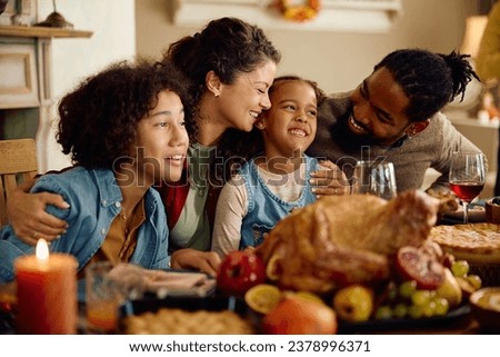 Happy parents and their kids enjoying during Thanksgiving meal at dining table. 