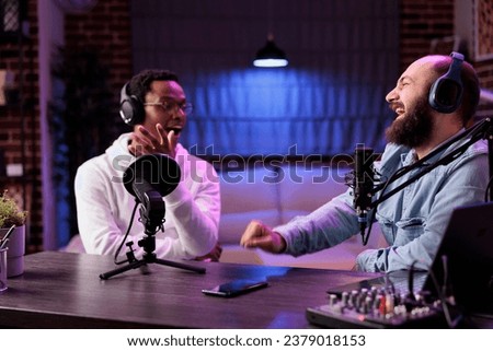 African american host engaging in entertaining discussion with celebrity during live stream in professional studio, making him laugh. Presenter using high quality equipment to produce comedy podcast
