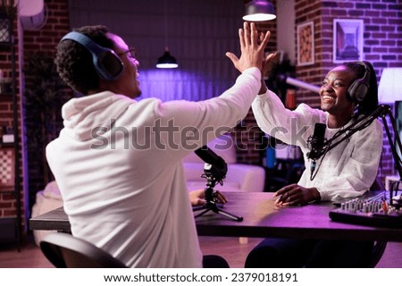 Cheerful online show host high fiving smiling african american guest after successful podcast. Interviewer broadcasting live from living room studio, happy after reaching donations goal