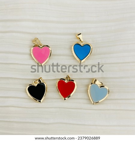 Golden basket necklaces on white background shot close up, heart locket for photos, keychains, colored heart charms Royalty-Free Stock Photo #2379026889
