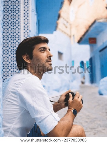 Male tourist with photo camera enjoying architecture of ancient blue city