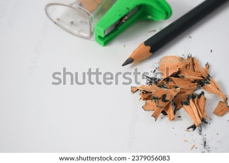 green pencil sharpener and dark green pencils, pencil shavings on white background
