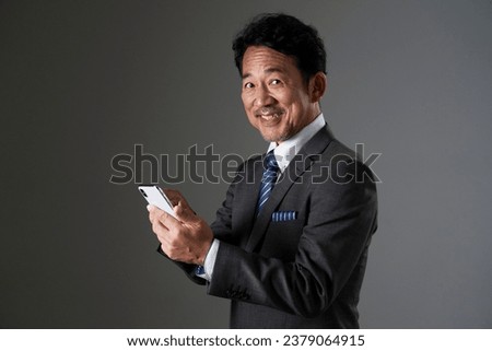 Asian middle aged businessman using the smartphone in black background