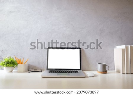 Laptop computer, coffee cup, potted plant and picture frame on creative workplace. Blank screen for your advertising text.