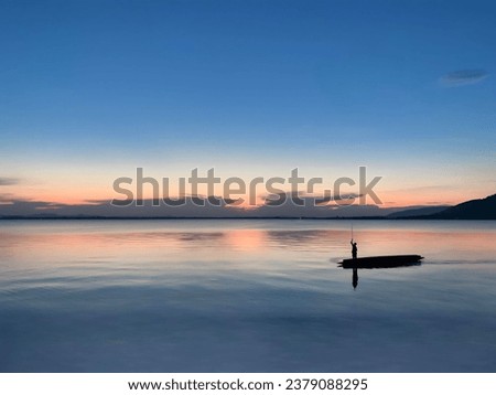 A picture of the way of life of villagers who row small boats to go fishing in the evening when the sun is about to set on the horizon. It's a landscape photo. Between the sky and the river