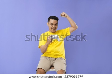 Photo of asian man enjoy and have fun play game console standing on purple colour background