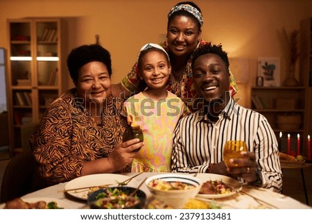 Happy grandmother, granddaughter and parents gathered at Kwanzaa dinner table