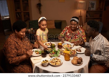 Happy Black family eating dinner together celebrating Kwanzaa