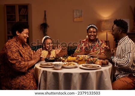 Happy family clapping before eating dinner, celebrating Kwanzaa at home