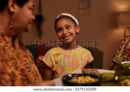 Portrait of smile preteen girl talking to mother at Kwanzaa family dinner