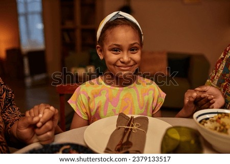 Portrait of happy girl hold hands of her parents when praying before Kwanzaa dinner