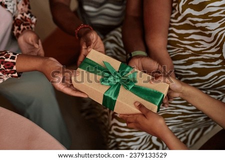 Closeup image of family giving Zawadi gift to little girl at Kwanzaa celebration