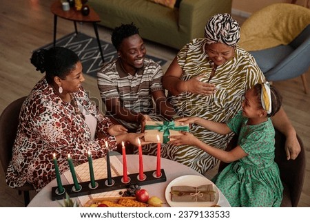 Happy parents giving daughter Zawadi, gift for Kwanzaa celebration