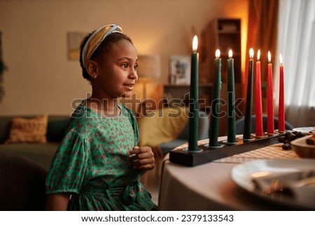 Dreamy smile Black girl looking at colorful candles representing struggle, hope and heritage