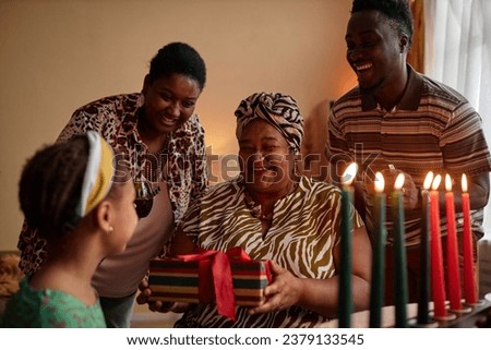 Black family giving present to preteen girl at Kwanzaa celebration