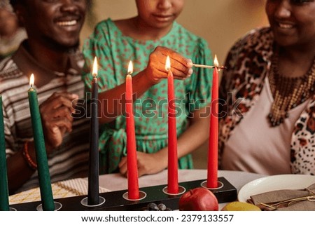 Cropped image of family lightning colorful candles on dinner table