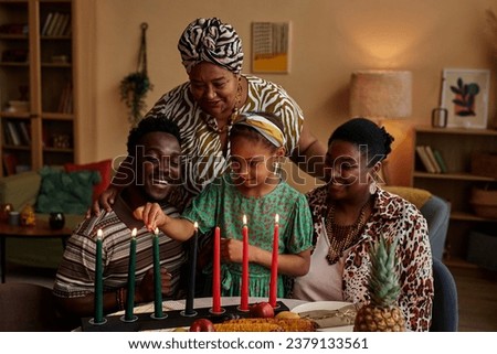Black three generation family lightning Mishumaa Saba, seven colorful candles for Kwanzaa celebration