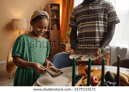 Father teaching daughter to serve table for Kwanzaa dinner