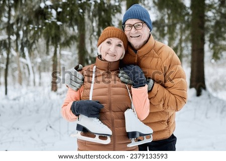 Portrait of happy excited senior couple with ice skates standing in city park