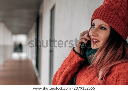 smiling urban young woman in winter clothes using phone on the street