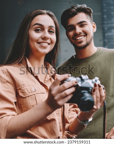 Portrait of cheerful male and female friends spending free time on hobby using vintage camera in city