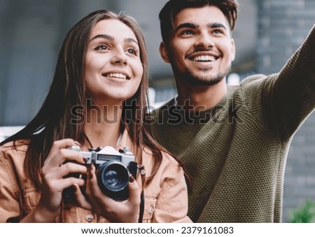 Cheerful couple in love spending time together on date using vintage camera for making photos