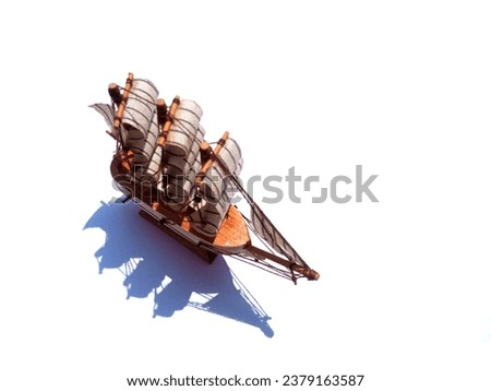 an isolated of a toy sailing ship on white background with high contrast shadow  Royalty-Free Stock Photo #2379163587