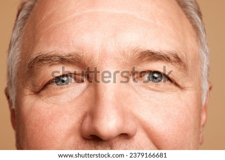 Close-up cropped photo of middle aged, 45s male face, eyes, brows isolated beige studio background. Concept of natural beauty, skincare, health care, facial expression, anti-aging and spa treatment.