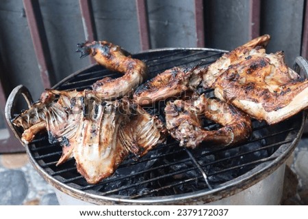 Grilling seasoned chicken in grates on charcoal bbq.