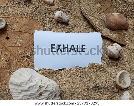 Exhale writing on beach sand background.