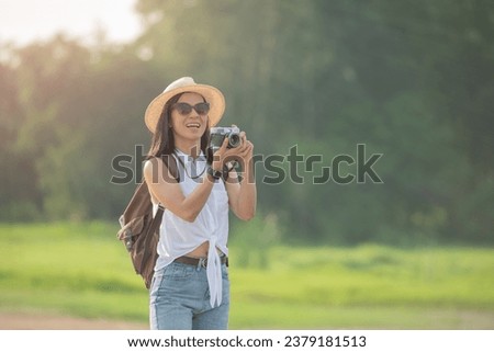 Hipster woman with backpack taking photo of amazing landscape sunset on vintage camera on peak mountain. Joyful asian woman travel vacation. Tourist traveler on background sunlight in trip in nature
