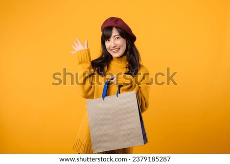 Young Asian woman 30s, wearing a yellow sweater and red beret, embraces the joy of shopping against a vibrant yellow backdrop.