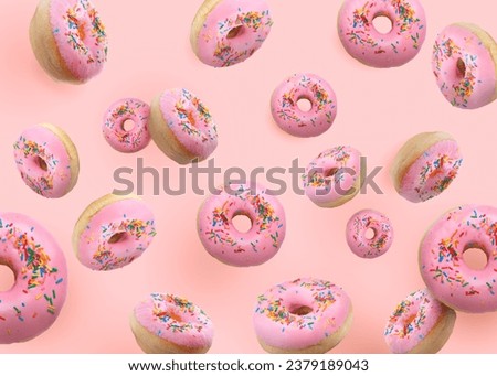 Tasty donuts decorated with sprinkles falling on pink background Royalty-Free Stock Photo #2379189043