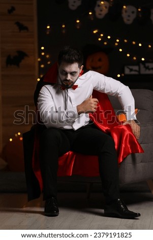 Man in scary vampire costume against blurred lights indoors. Halloween celebration
