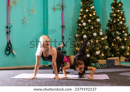 Beautiful woman and a girl go in for sports at Christmas near a decorated Christmas tree, sports and holiday. High quality photo.