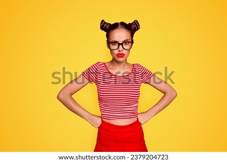 Strict teacher Portrait of grimacing offended young gorgeous woman model with with hands on waist and bun hairstyle isolated on red background
