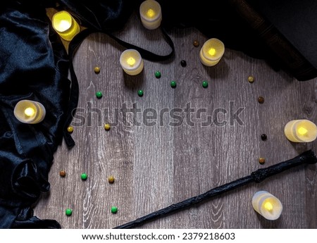 Halloween theme picture with old book, candies,candles, cape and magic wand. copy space.