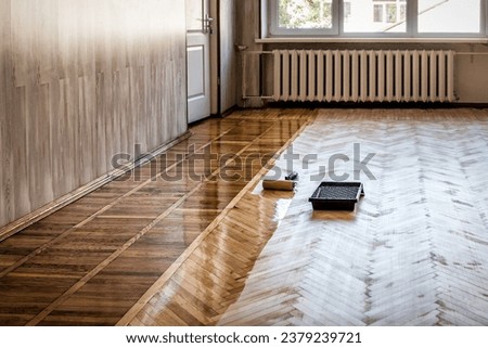 Lacquering wood floors. A roller to coating floors. Varnishing lacquering parquet floor by paint roller - second layer. Home renovation parquet. Industrial theme Royalty-Free Stock Photo #2379239721