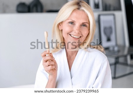 Healthy white toothy smile. Everyday brushing teeth. Oral hygiene and dental care concept. Portrait of woman in robe holding bamboo toothbrush in bathroom. Whitening at home. Royalty-Free Stock Photo #2379239965