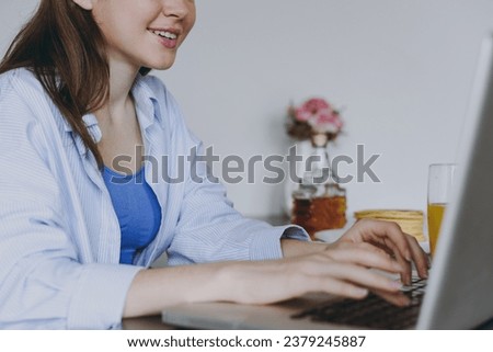 Cropped up photo shot of young housewife woman 20s in casual clothes eat breakfast use laptop pc computer look for recipe drink juice cook food in light kitchen at home Healthy diet lifestyle concept