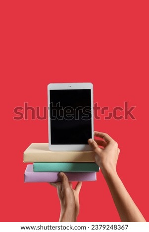 Woman with blank tablet computer and books on red background