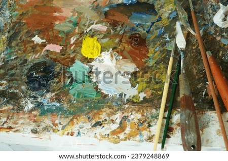 Multiple colors , Palette knives and brushes placed on the palette.