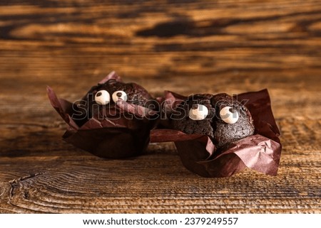 Delicious chocolate cupcakes in paper for Halloween celebration on wooden background, closeup