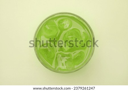 Glass of delicious iced matcha tea on green background, top view