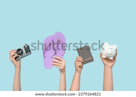 Female hands with photo camera, flip flops, passport and piggy bank on blue background. Travel concept
