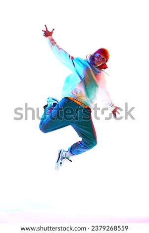 Man in his 30s wearing sport style clothes and dancing breakdance isolated over white studio background in neon light. Concept of contemporary dance, street style, fashion, hobby, youth. Ad