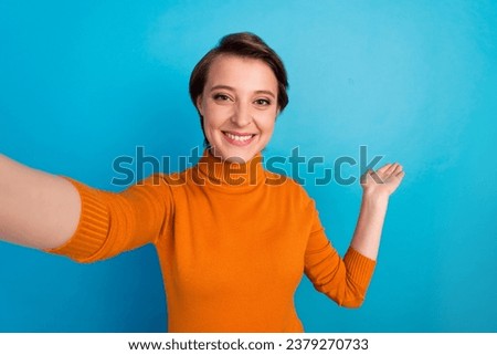 Selfie of young blogger woman make video showing novelty empty space isolated blue color background.